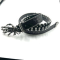 Black leather belt with skeleton hand design and studs on a white background