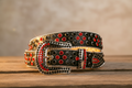 Black studded belt with red stones and silver buckle, textured edge