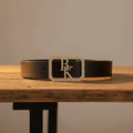 Black leather belt buckle with rhinestone frame and central two-letter initial